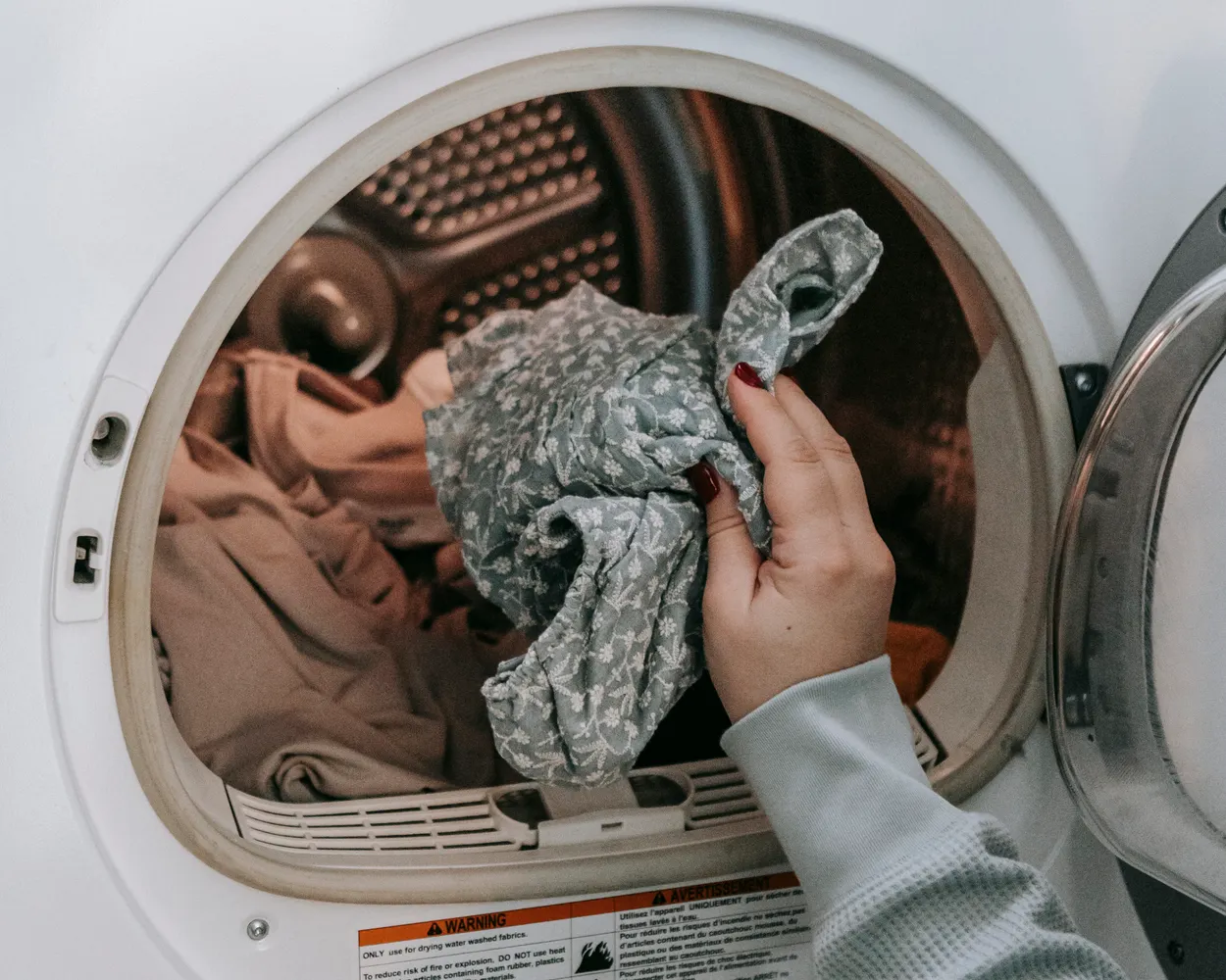 A front-load washing machine being loaded in a home laundry area